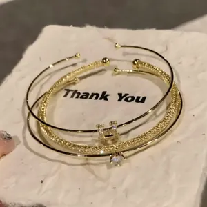 Elegante set di bracciali placcati oro 18K con zirconi e lettera H su base bianca testurizzata