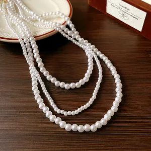 Dettaglio di un elegante collana di perle artificiali bianche multistrato su legno