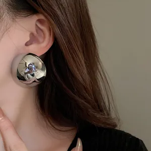 Detailed close-up showing the high-polished silver metallic dome earring on model
