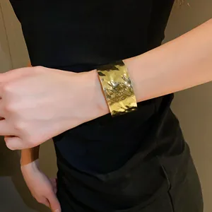 Primo piano che mostra la texture increspata di un bracciale a polsino dorato aperto