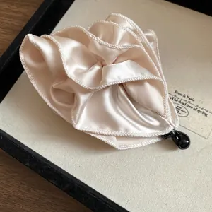 Dettaglio macro del design a fiore in tessuto satinato plissettato su un fermaglio beige
