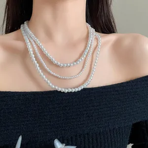 Elegante collana di perle artificiali multistrato su top in maglia nera.