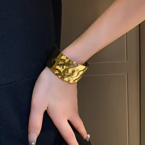 Dettaglio di un elegante bracciale a polsino aperto dorato con pieghe irregolari