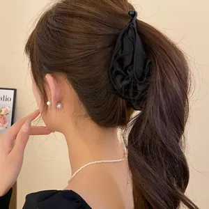 Vista dettagliata di un'elegante clip per capelli a fiori in tessuto nero plissettato
