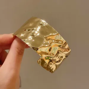 Vista dettagliata di un ampio bracciale a polsino dorato martellato irregolare di lusso