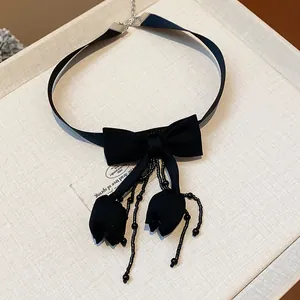 Primo piano di un elegante choker in tessuto nero con fiocco e nappine a tulipano