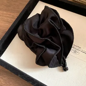 Primo piano di un'elegante fermaglio per capelli a fiore in tessuto plissettato nero satinato