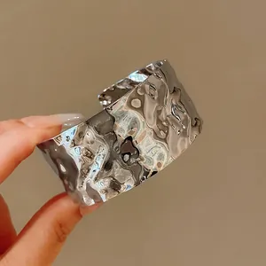 Primo piano della trama metallica stropicciata irregolare del bracciale argento