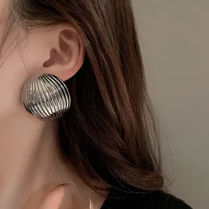 Detailed view of silver metallic striped semi-circular stud earrings with ribbed texture.