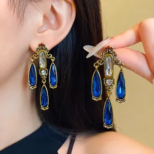Vintage palace style chandelier earrings with blue water drop crystals and silver needles.