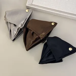 Dettaglio di eleganti mollette per capelli triangolari in raso argento, marrone e nero
