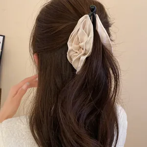 Dettaglio di un elegante fermaglio per capelli a fiore in tessuto beige su mora