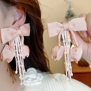 Dettaglio degli orecchini a fiocco in tessuto rosa con eleganti nappe di perline