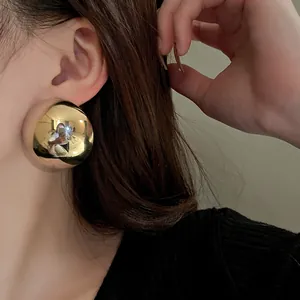 Close-up detail of a shiny gold metallic dome stud earring worn on an Asian model's ear