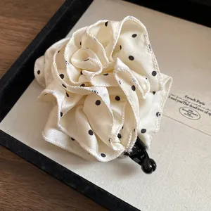 Dettaglio di un'elegante fermaglio per capelli a fiori a pois in tessuto color crema
