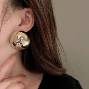 Detailed close-up view of an exaggerated gold hemispherical stud earring on an Asian model's ear