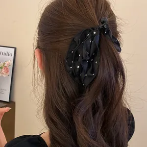 Primo piano di un fermaglio per capelli a fiore in tessuto nero a pois su capelli