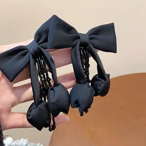 Primo piano di eleganti orecchini a fiocco in tessuto nero con nappe di perline nere