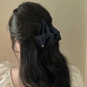 Dettaglio di una molletta per capelli a triangolo in raso nero su un'acconciatura