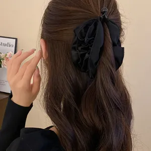 Primo piano di un'elegante molletta per capelli a fiore in tessuto nero su capelli.