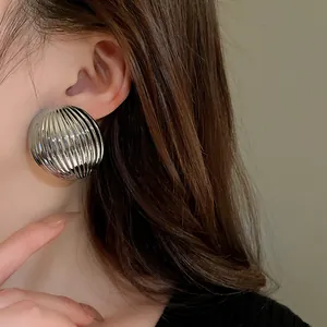Detailed view of silver metallic striped semi-circular stud earrings worn on ear