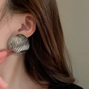 Close-up of metallic striped semi-circle stud earrings on model for a trendy look