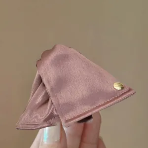 Primo piano di una pinza per capelli a triangolo in raso malva con targhetta in oro