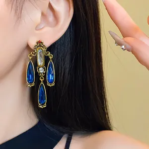 Close-up of elegant vintage palace style gold-tone earrings with blue crystal drops