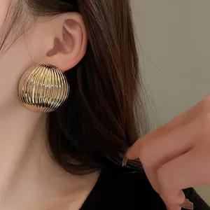 Close-up detail of golden semi-circular earrings with vertical striped texture.