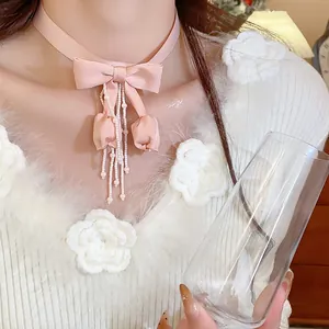 Dettaglio di una collana girocollo rosa con fiocco in tessuto, nappe e tulipani