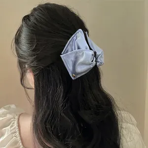 Dettaglio ravvicinato di un fermaglio a triangolo in raso blu su lunghi capelli mossi