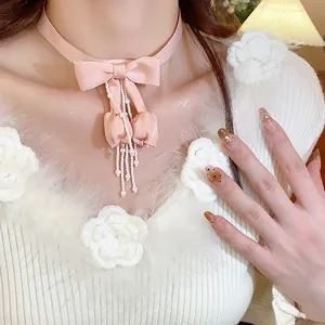 Primo piano di un girocollo in tessuto rosa con fiocco ed eleganti nappe di perline.