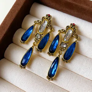 Detail view of vintage teardrop earrings with blue stones in an antique gold finish