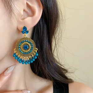 Close-up of ethnic style gold-tone earrings with blue rhinestones and tassels