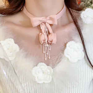 Dettaglio choker in nastro rosa con fiocco e nappine di perline a forma di tulipano.
