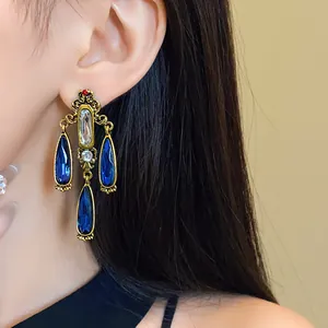 Macro detail view showing a vintage-style tassel earring with blue gemstones worn on ear
