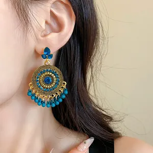 Detailed shot of ethnic style golden earring with blue rhinestones and beads on ear