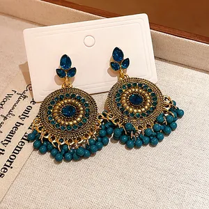 Detailed macro shot of ethnic style gold tassel earrings with vibrant blue crystals