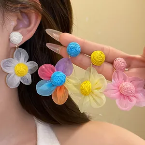 Detalle de pendientes de flores de rafia y gasa en varios colores pastel vibrantes