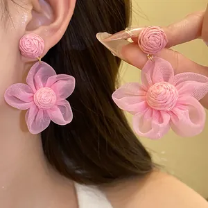 Detalle de los pendientes de flores de rafia y gasa rosa en una linda modelo asiática