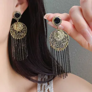 Detailed view of vintage gold coin tassel earrings featuring black chain drops and filigree