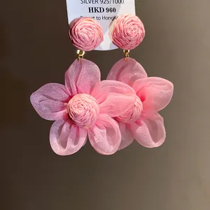 Vista detallada de pendientes de flores de rafia y gasa rosa con aguja de plata 925
