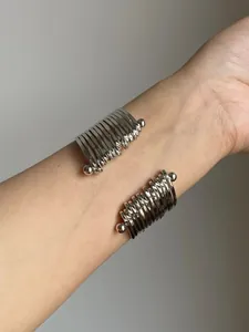 Detail of a silver-toned multi-layer pleated metal cuff bracelet on a wrist