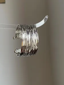 Macro view of silver multi-layered pleated texture on a wide metal open cuff bracelet