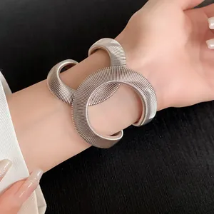 Primer plano de un brazalete elástico cruzado con nervaduras plateadas en la muñeca