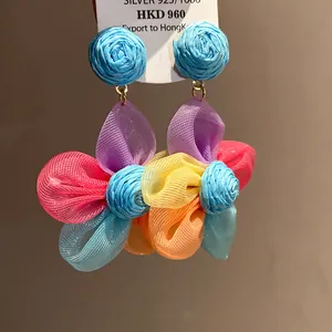 Vista macro de pendientes de flores de rafia y gasa de colores con aguja de plata