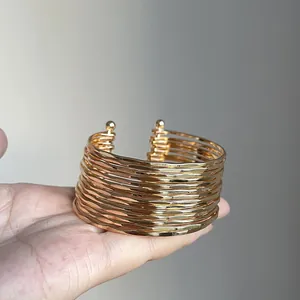 Close-up detail of a wide multi-layered gold metal cuff bracelet with a wrinkled texture.