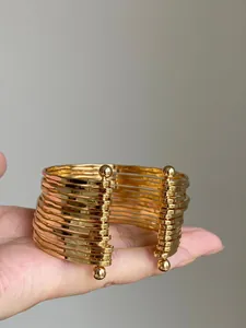 Detailed view of a stylish gold pleated multi-layer open cuff bracelet held in hand