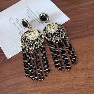 Detail view of vintage bohemian tassel earrings with coin medallion and black chain