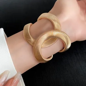 Detalle de un lujoso brazalete elástico entrelazado en forma de serpiente dorada en la muñeca